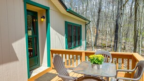 A wooden deck with a glass table and chairs, a potted plant, and a view of a forest. - Alpine Lake Resort Cabin Rental w/ Pool Access! (Terra Alta)