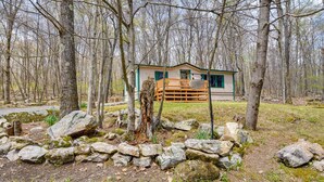 A cabin with a wooden deck surrounded by rocks and trees. - Alpine Lake Resort Cabin Rental w/ Pool Access! (Terra Alta)