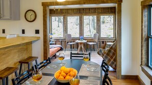 A dining area with a wooden table, chairs, a bowl of oranges, and wine glasses. - Alpine Lake Resort Cabin Rental w/ Pool Access! (Terra Alta)