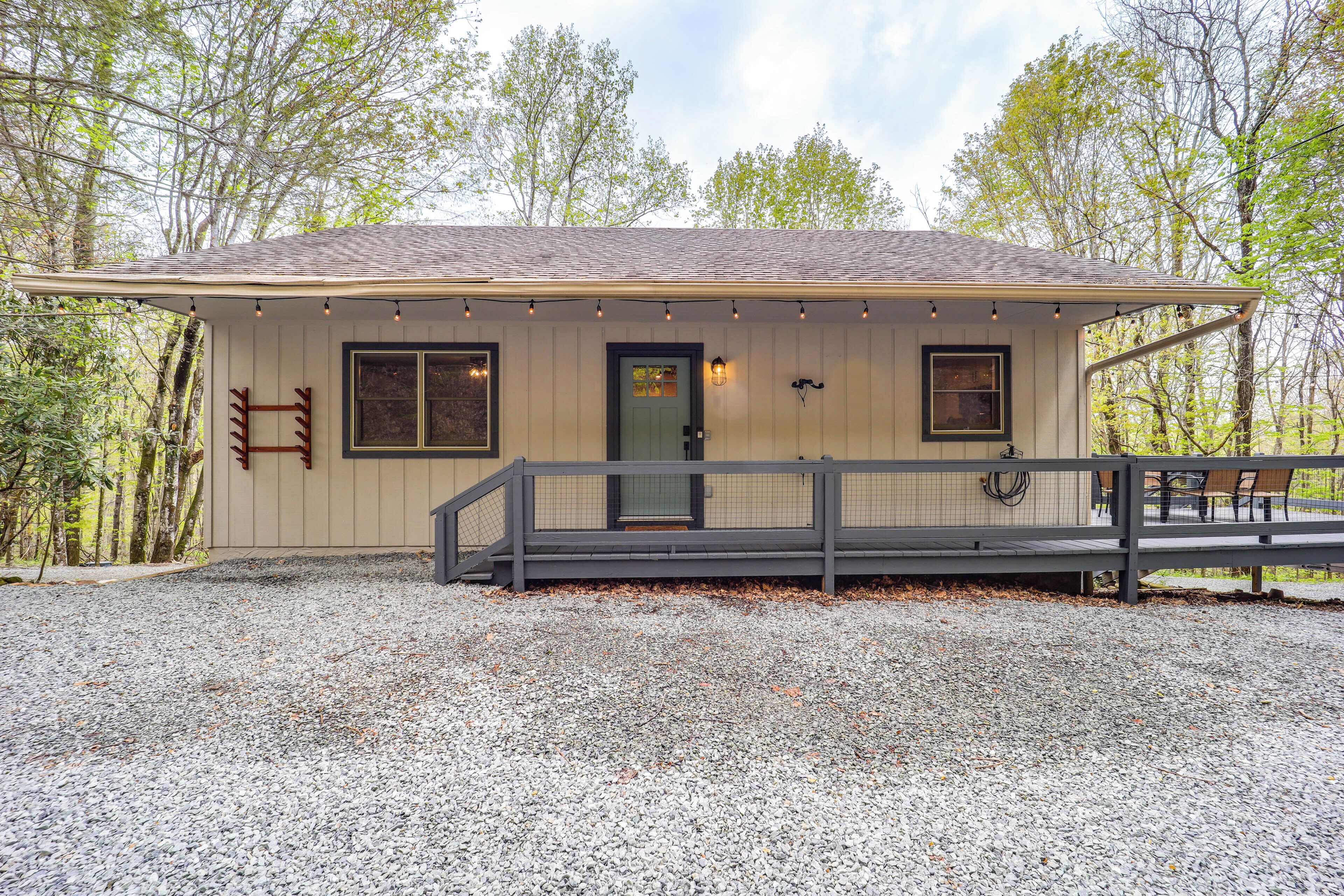 A single-story house with a gravel driveway, a front porch with a railing, and a small deck.