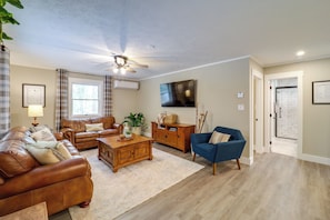 A living room with a brown leather sofa, a blue armchair, a wooden coffee table, and a ceiling fan.