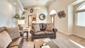 A living room with a brown leather sofa, a coffee table, and a lamp. There is a dining table with chairs and a plant. - Lake Havasu City Escape w/ Pool, Patio & Grill! (Lake Havasu City)