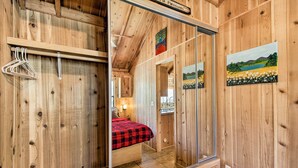 A wooden-paneled room with a bed, a mirror, and a painting on the wall. - Lakeside Cabin w/ Fire Pit ~ 4 Mi to Show Low Lake (Lakeside)