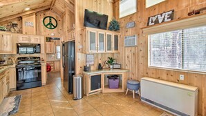 A wooden cabin interior with a kitchen, a large window, and a mounted television. - Lakeside Cabin w/ Fire Pit ~ 4 Mi to Show Low Lake (Lakeside)