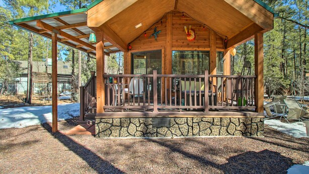 A wooden cabin with a stone foundation, a covered porch with chairs, and a view of the surrounding forest. - Lakeside Cabin w/ Fire Pit ~ 4 Mi to Show Low Lake (Lakeside)