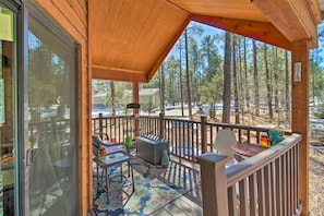 A wooden deck with a glass door leading to a room, a small table, a chair, and a decorative statue.