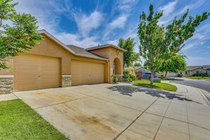 A residential garage with a stone facade, a clear driveway, and a well-maintained lawn. - Peaceful Fresno Home, Near Popular Wineries! (Fresno)