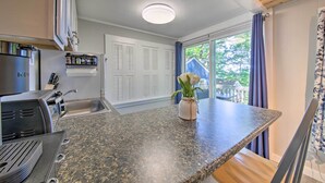 A kitchen with a granite countertop, a built-in grill, and a window with curtains. - Lush Edgecomb Studio Cottage w/ Fire Table! (Edgecomb)