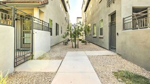 A narrow alleyway between buildings with a gravel path, metal gates, and small trees. - 6 Mi to Dtwn Chandler: Newly Built Townhome (Chandler)
