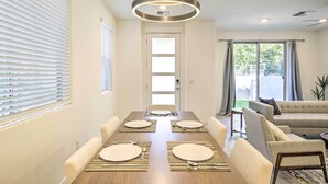 A dining area with a wooden table set for four, a sofa, and a view of the outdoors. - 6 Mi to Dtwn Chandler: Newly Built Townhome (Chandler)