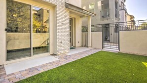 A modern building with a brick facade, large sliding glass doors, and a small grassy area in front. - 6 Mi to Dtwn Chandler: Newly Built Townhome (Chandler)