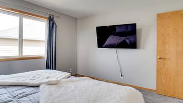 A bedroom with two beds, a TV mounted on the wall, and a wooden door.