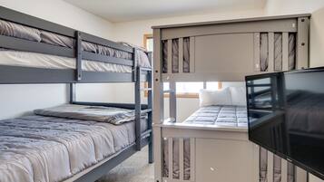 A bunk bed room with a television on the lower bunk.