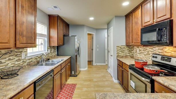 A kitchen with wooden cabinets, a stainless steel refrigerator, a microwave, and a stove. - Huntsville Vacation Rental < 5 Mi to Airport! (Huntsville)