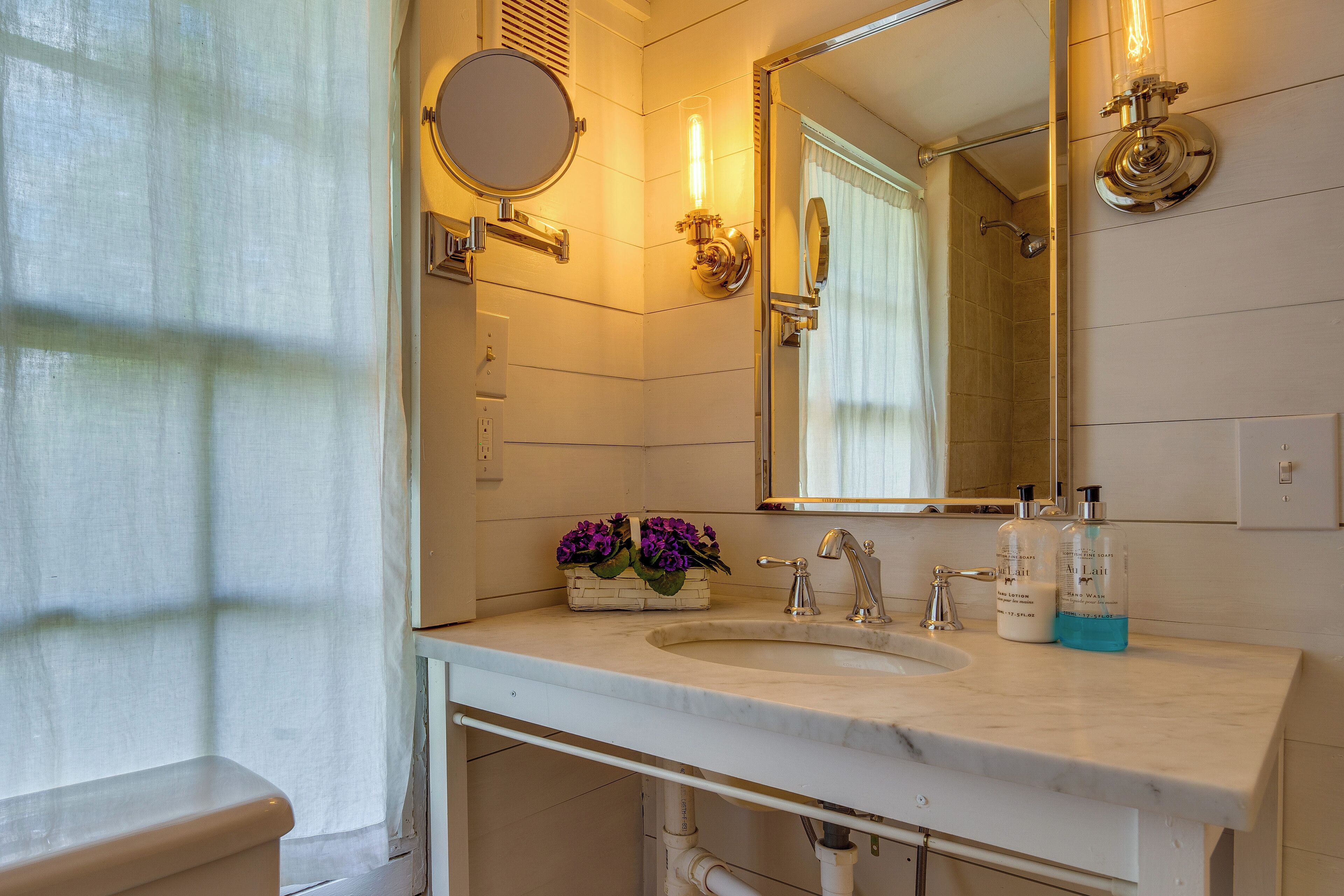 A bathroom with a sink, mirror, and shower.