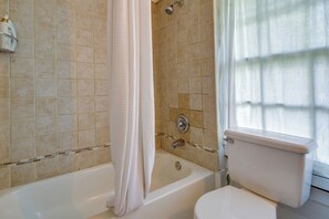 Un baño con bañera, inodoro y paredes de azulejos.