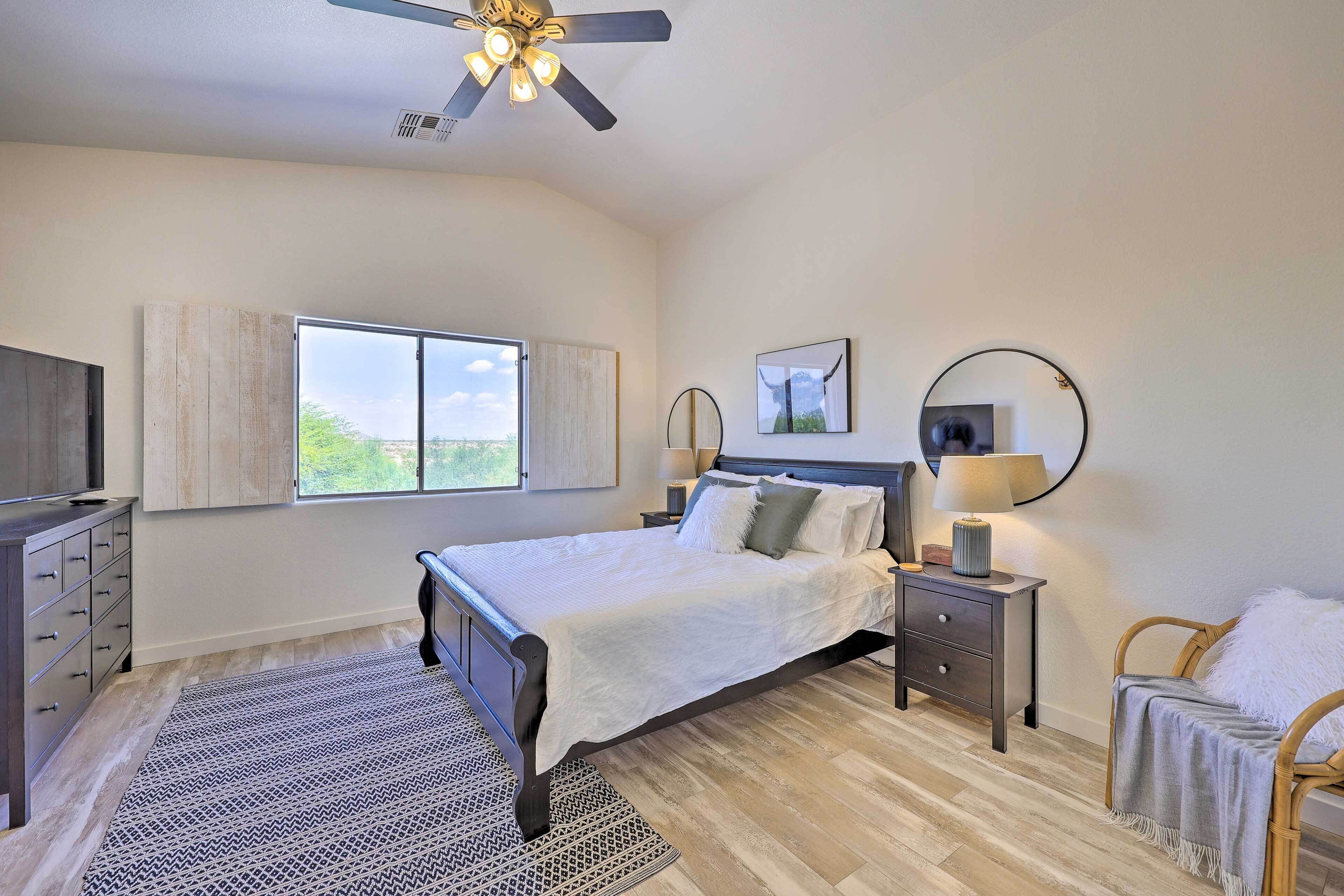 A bedroom with a bed, bedside tables, a chair, a TV, and a window with curtains.