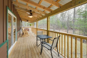 A wooden deck with a table and chairs, large windows, and a ceiling fan. - Scenic Murphy Cabin w/ Hot Tub, Fire Pit & Views (Murphy)