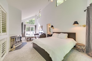 A modern bedroom with a large bed, a desk, and a chair. There is a window with blinds, a radiator, and a lamp on the wall. - 10 Mi to Nubs Nob: Modern Retreat w/ Fire Pit (Harbor Springs)