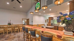 A spacious kitchen with a long wooden bar, bar stools, and a decorative vase with blue flowers. - Riverfront 'heaven on the White' w/ Covered Patio! (Norfork)
