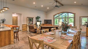 A spacious kitchen with a wooden island, bar seating, and a large dining table with placemats. - Riverfront 'heaven on the White' w/ Covered Patio! (Norfork)