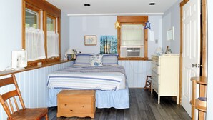 A bedroom with a bed, a wooden chair, a dresser, a window with curtains, and a painting on the wall. - Cozy Waterfront Cottage on Montsweag Bay! (Wiscasset)