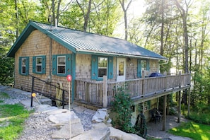 A cabin with a deck, surrounded by trees.
