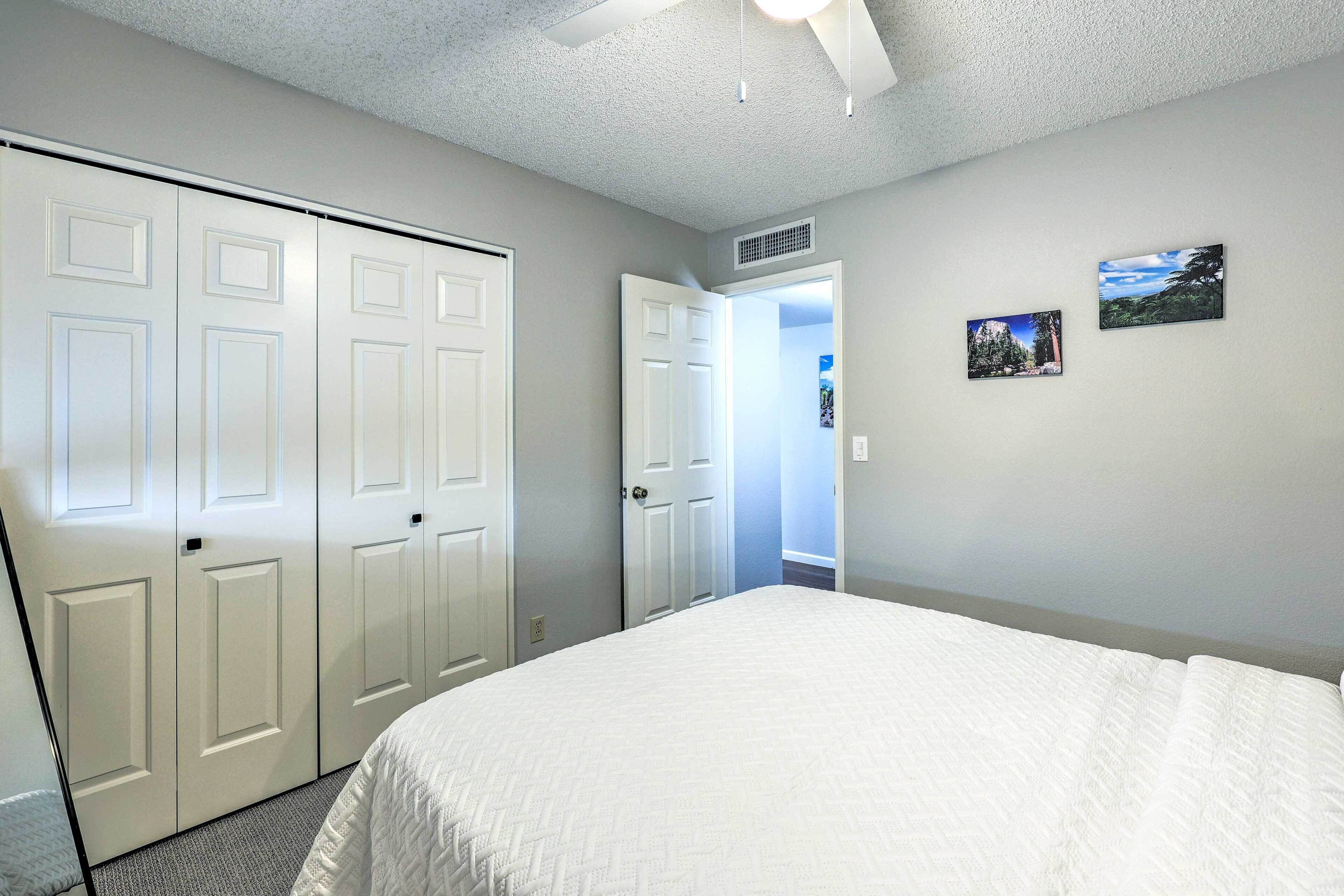 A bedroom with a bed, a closet, and two framed pictures on the wall.