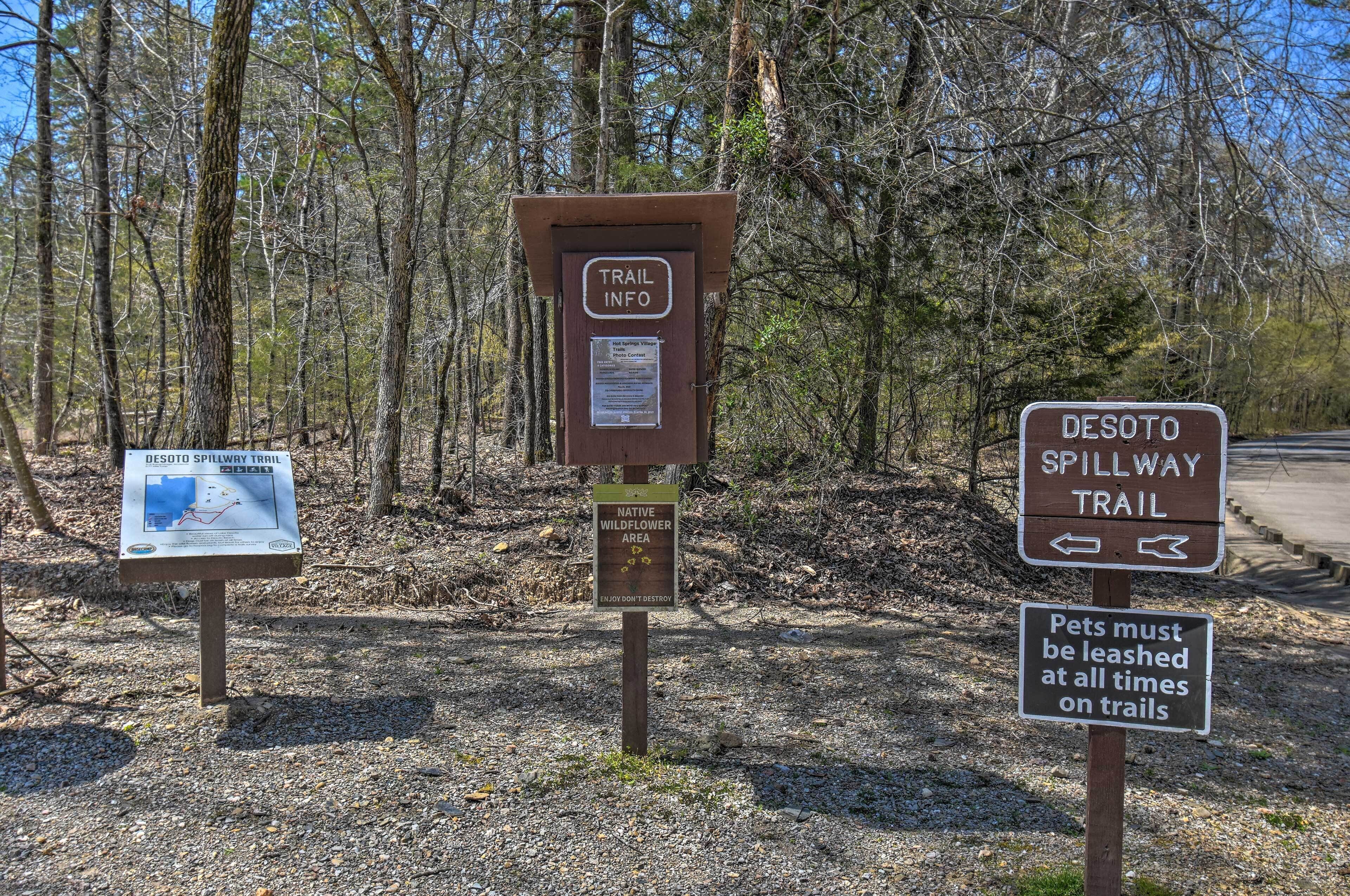 A trail sign with information about the Desoto Spillway Trail and a notice about pet leash requirements.