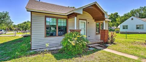 A single-story house with a front porch, a chimney, and a small garden area.