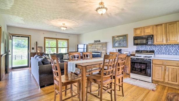 Une cuisine spacieuse avec des meubles en bois, une table à manger et des chaises. On y trouve également une cheminée en pierre, un four à micro-ondes et une cuisinière.