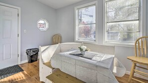 A room with a bed, a table with a tablecloth, two windows with blinds, a chair, a trash can, and a no smoking sign on the wall. - Middletown Township Home, Close to Beaches! (Leonardo)