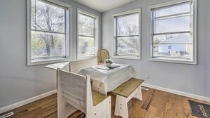 A dining area with a table set for two, flanked by two chairs, and three windows with blinds. - Middletown Township Home, Close to Beaches! (Leonardo)