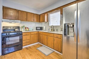 Una cocina con armarios de madera, un refrigerador de acero inoxidable, un microondas y una estufa.