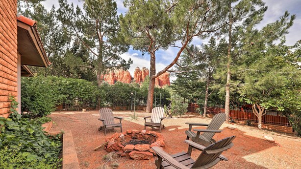 A patio area with a fire pit, wooden chairs, and a brick building.