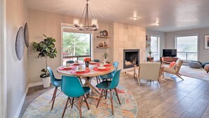 A dining area with a round table, teal chairs, and a chandelier.