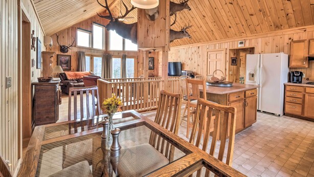 A wooden cabin interior with a dining area, kitchen, and living space.