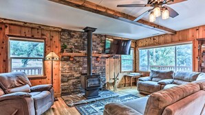 A cozy living room with a stone fireplace, leather sofas, and a television. - Rustic Oakhurst Retreat < 4 Mi to Bass Lake! (Oakhurst)