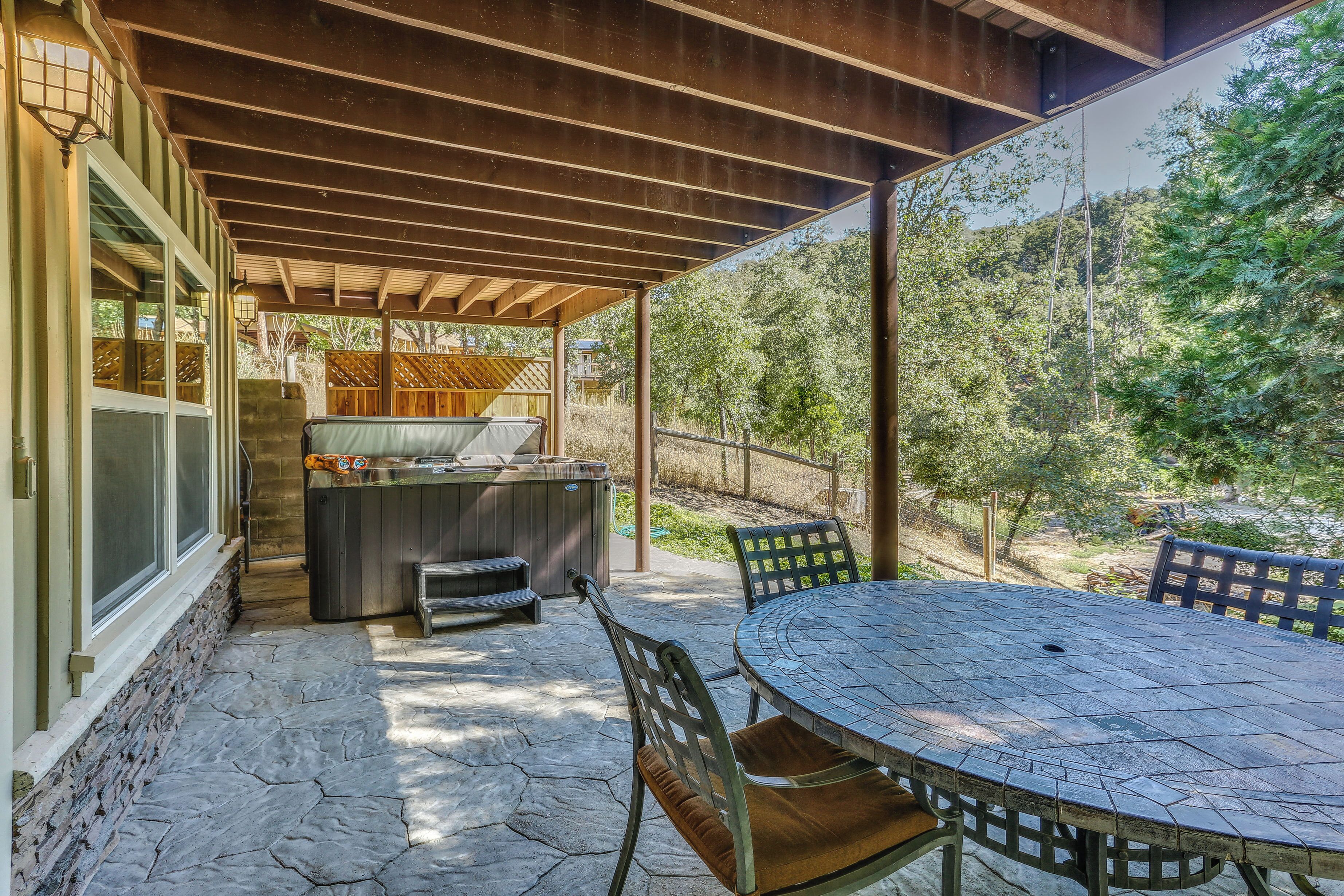 An outdoor patio with a stone floor, a round table, and chairs.