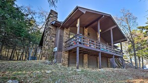 A stone cabin with a wooden deck and a covered porch. - Cozy Holiday Island Home: Hot Tub + Chiminea! (Eureka Springs)