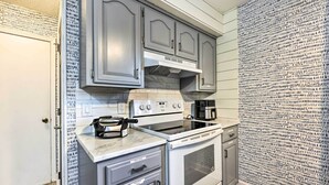 A kitchen with grey cabinets, a white countertop, and a patterned wallpaper. - Cozy Holiday Island Home: Hot Tub + Chiminea! (Eureka Springs)