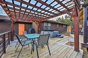 A wooden deck with a pergola, outdoor seating, and a table with chairs. - Cozy Holiday Island Home: Hot Tub + Chiminea! (Eureka Springs)