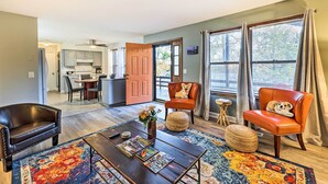 A living room with a coffee table, two leather chairs, a rug, and a dog resting on one of the chairs. - Cozy Holiday Island Home: Hot Tub + Chiminea! (Eureka Springs)
