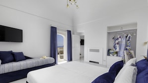 Quarto de hotel moderno com uma cama grande, um sofá, uma TV e um guarda-roupa.