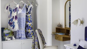 Quarto com guarda-roupa branco, espelho e uma pequena prateleira com objetos decorativos.