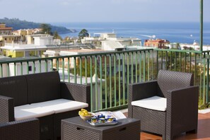 A balcony with wicker furniture, a tray of lemons, and a menu. - Maison Miramare in Sorrento (Sorrento)