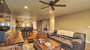 A spacious living room with a wooden coffee table, leather sofa, and a dining area in the background.