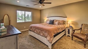 A bedroom with a bed, a nightstand, a chair, a desk, a ceiling fan, and a window.