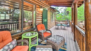 A wooden deck with wicker furniture, a green table, and a chair with orange cushions. - 3 Mi to Trails: Woodsy Retreat in Overgaard! (Overgaard)