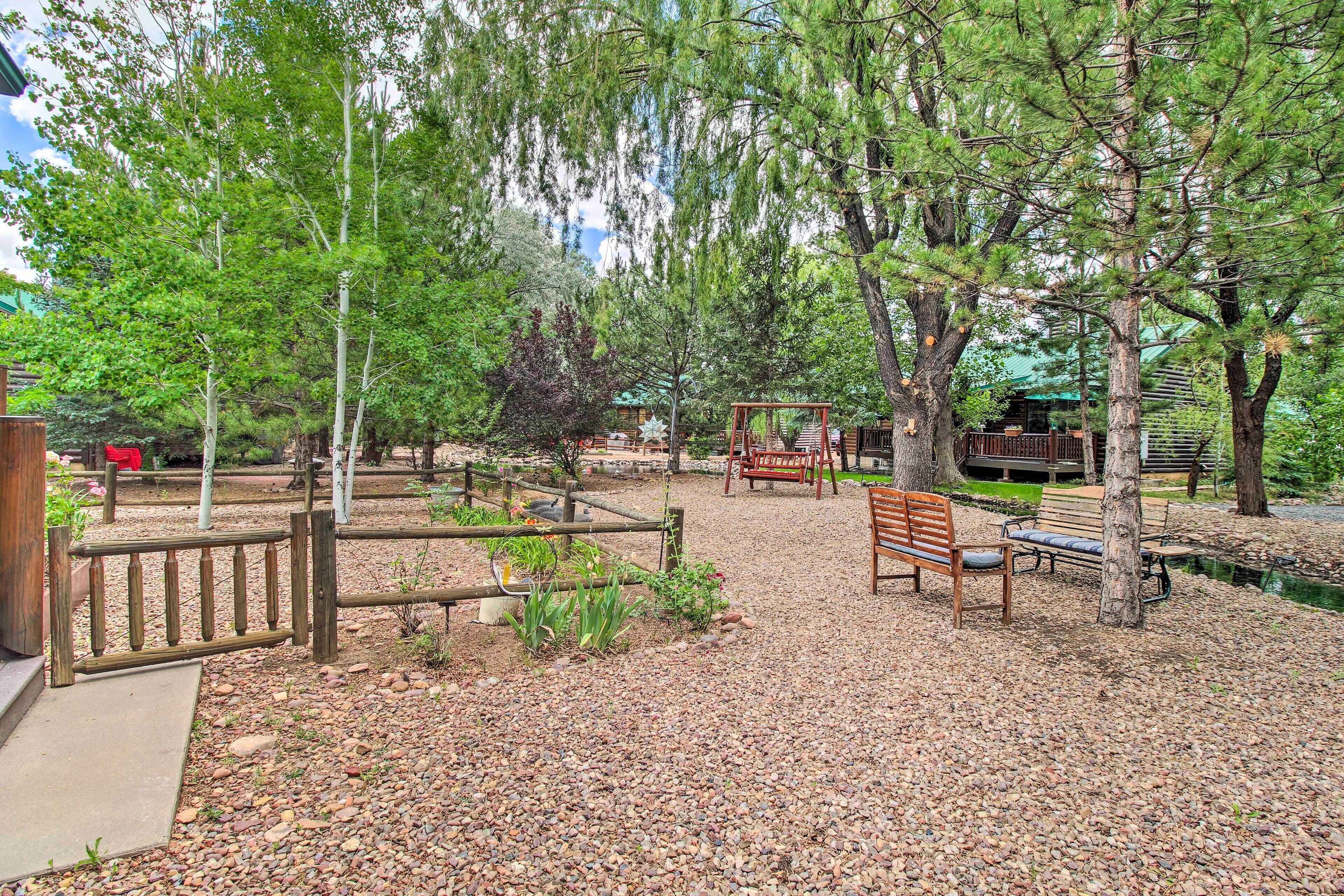 A park with wooden benches, a wooden fence, and trees.